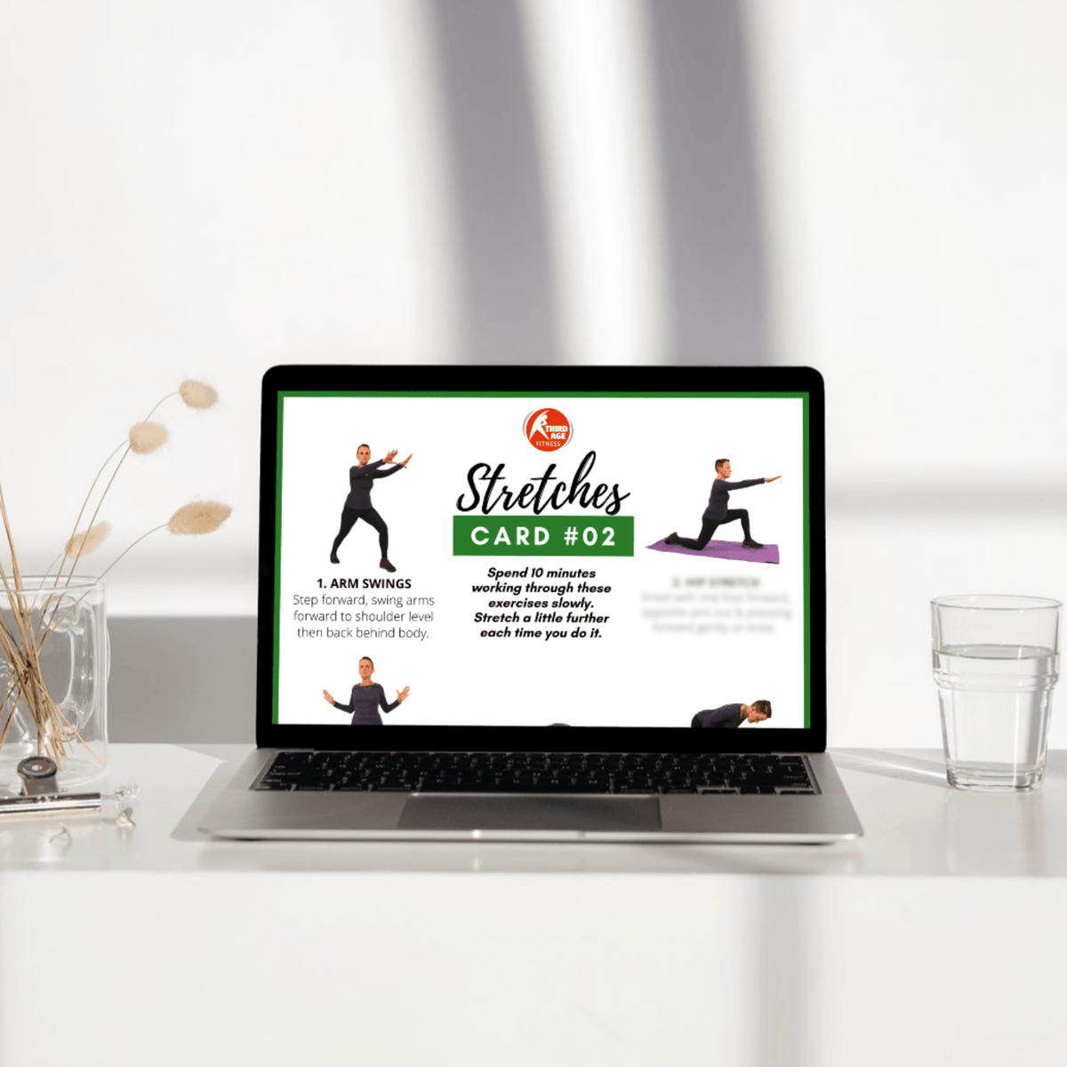 Laptop displaying a stretches card on a desk with a glass of water and decorative items.